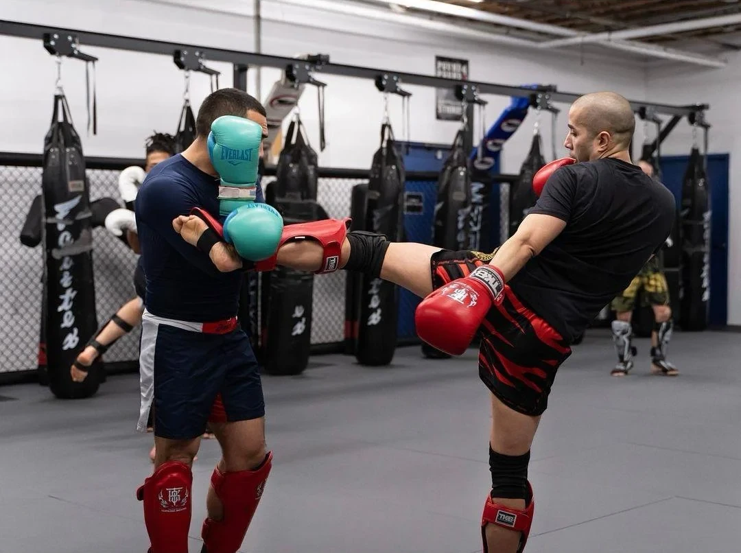 K-1 kickboxing student practicing a body kick with a partner at Pound 4 Pound in Littleton