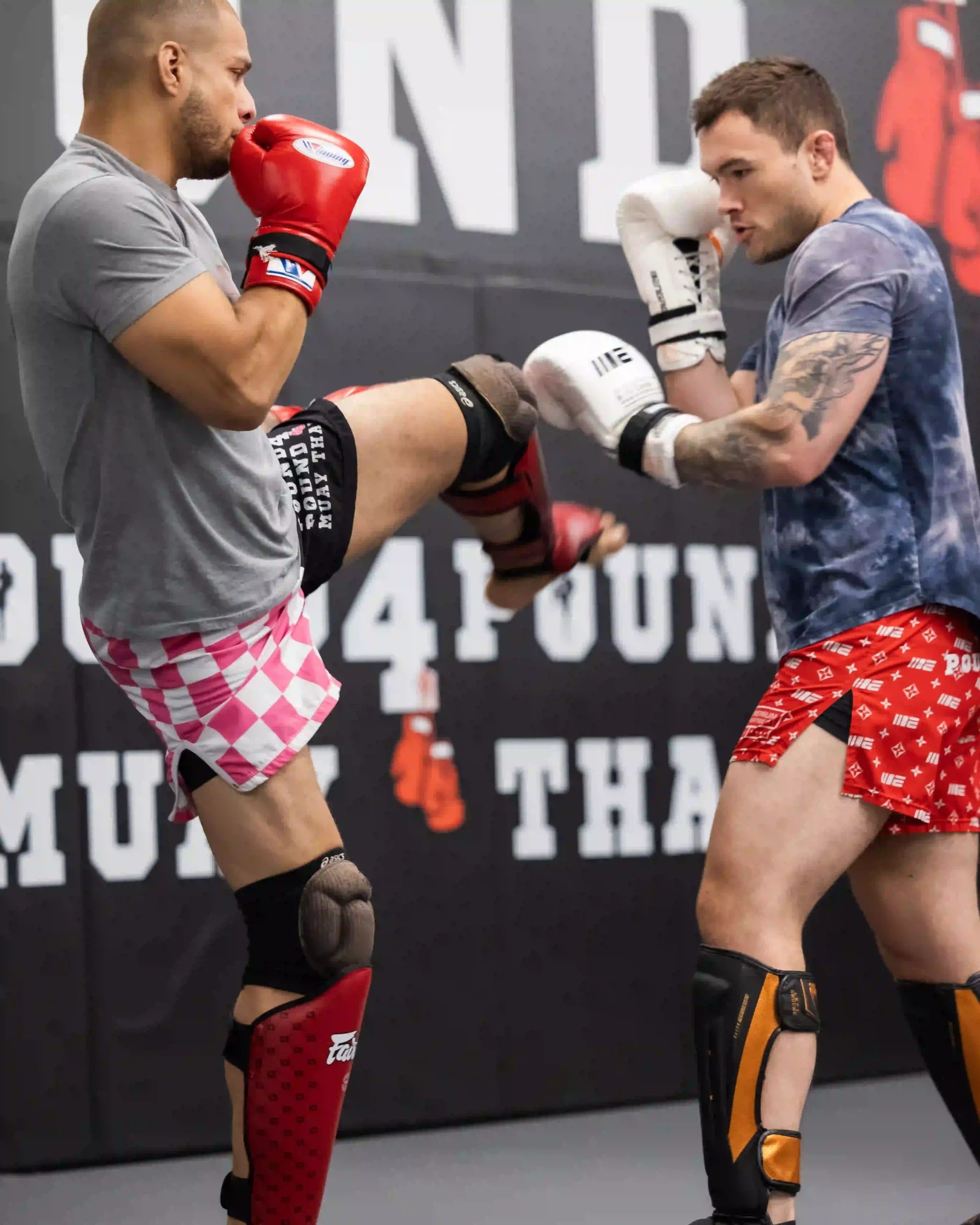 Two athletes practicing Muay Thai knee strikes during partner training at Pound 4 Pound Muay Thai in Littleton, Colorado